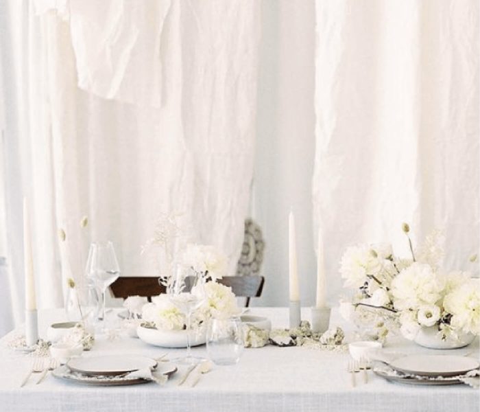 Mesa de casamento branca com pratos e flores brancas