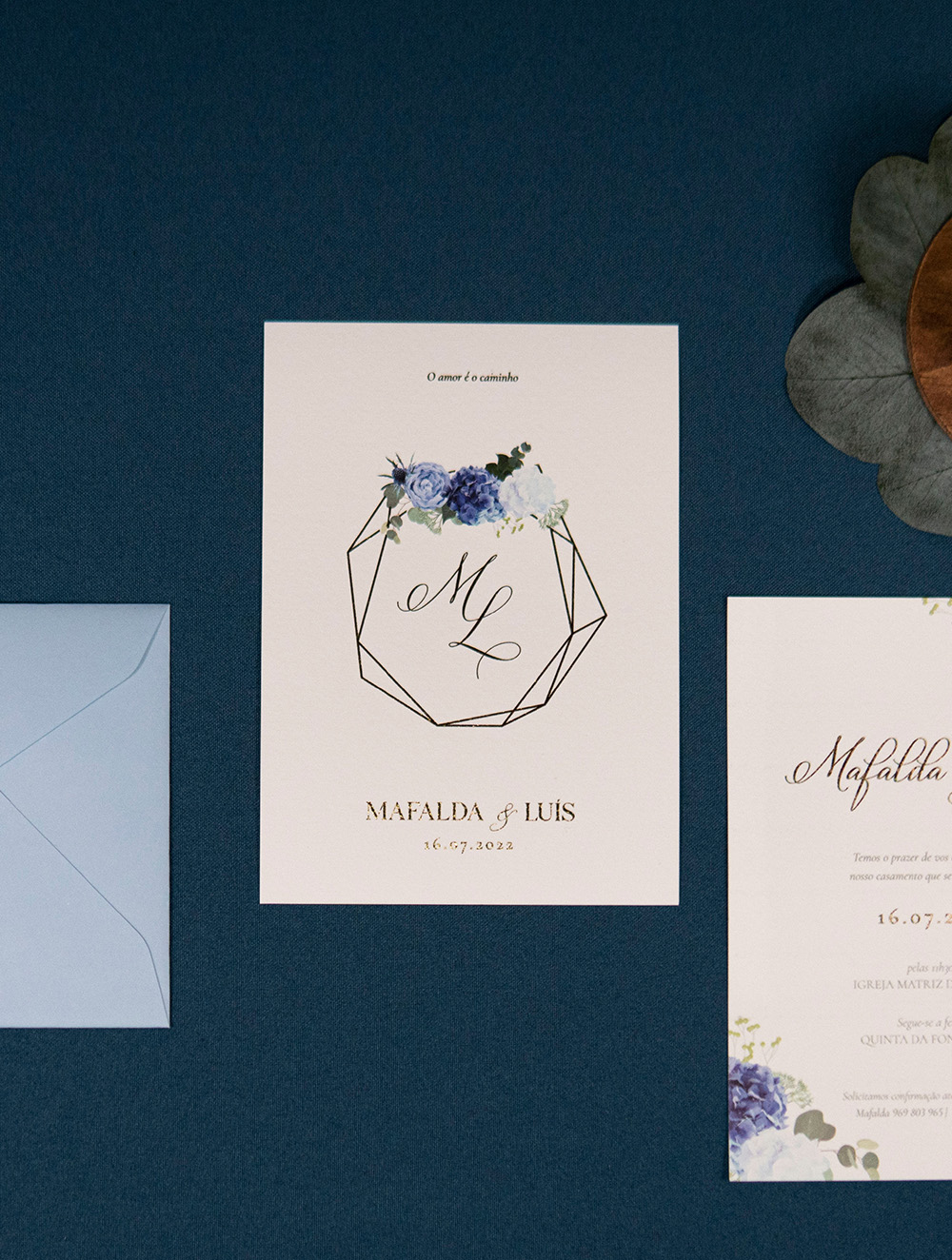 Convite de casamento com detalhes dourado e detalhes florais e envelope azul