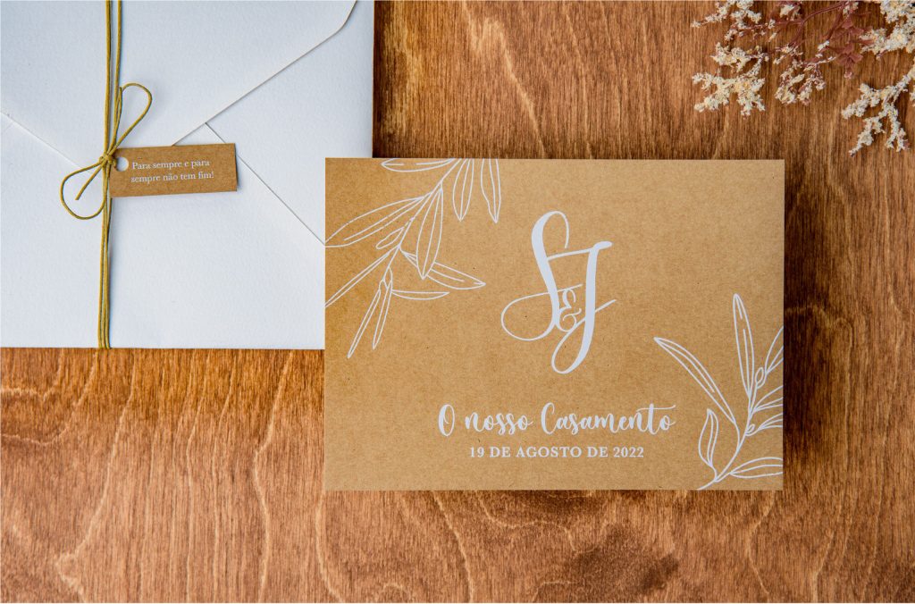 Convite de casamento em Kraft com detalhes florais e envelope branco com fio natural e uma etiqueta