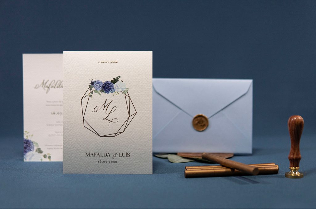 Convite de casamento com detalhes florais e detalhes em dourado e envelope branco com lacre dourado