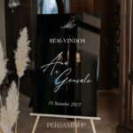 Placa de acrílico preto com detalhes florais em um cavalete de madeira
