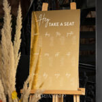 Placa de seating plan castanho com detalhes florais e cavalete de madeira