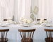 Mesa de casamento branca com pratos e flores brancas com cadeiras de madeira castanhas